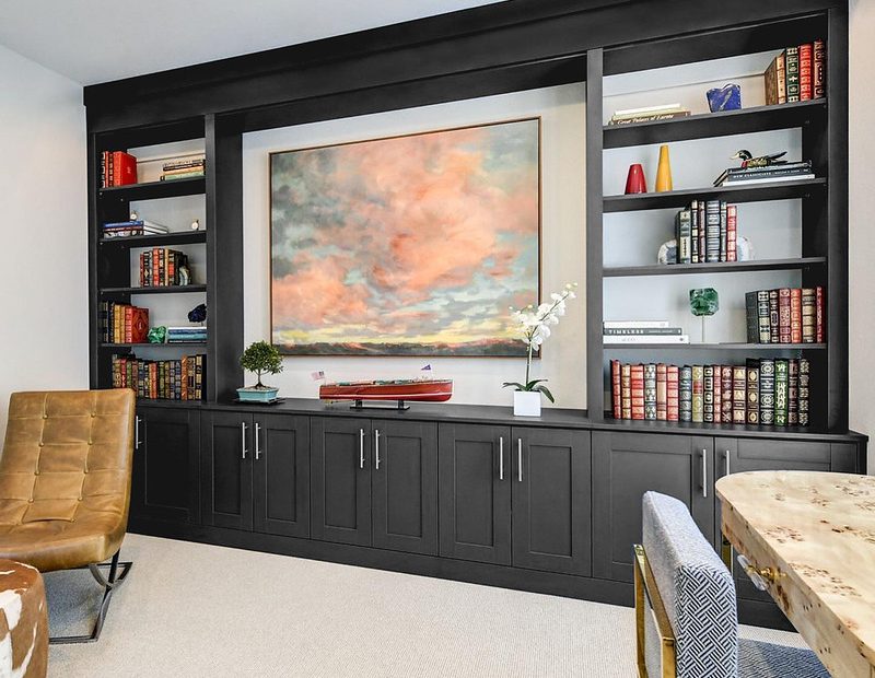 Sophisticated dark wood office library with custom shelving and integrated storage cabinets.