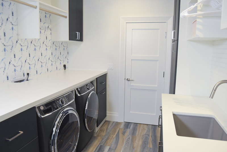 Streamlined custom laundry room with sleek black washer and dryer.