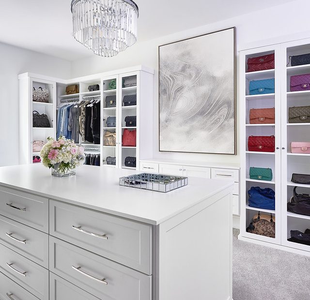 Bright white luxury walk-in closet with handbags displayed on shelves.