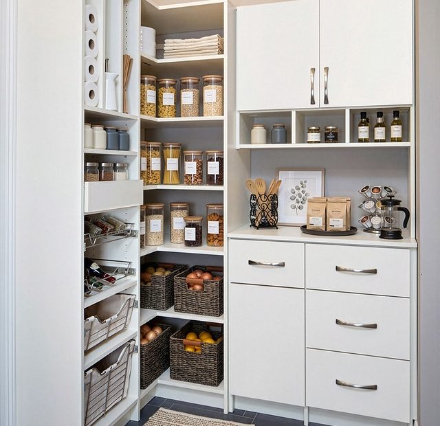 Small white pantry corner stocked with supplies and food in clear containers.