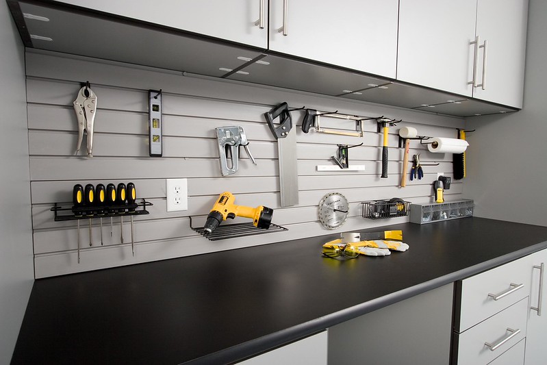 Garage workbench tabletop with organized tools hung on a grey slatwall.